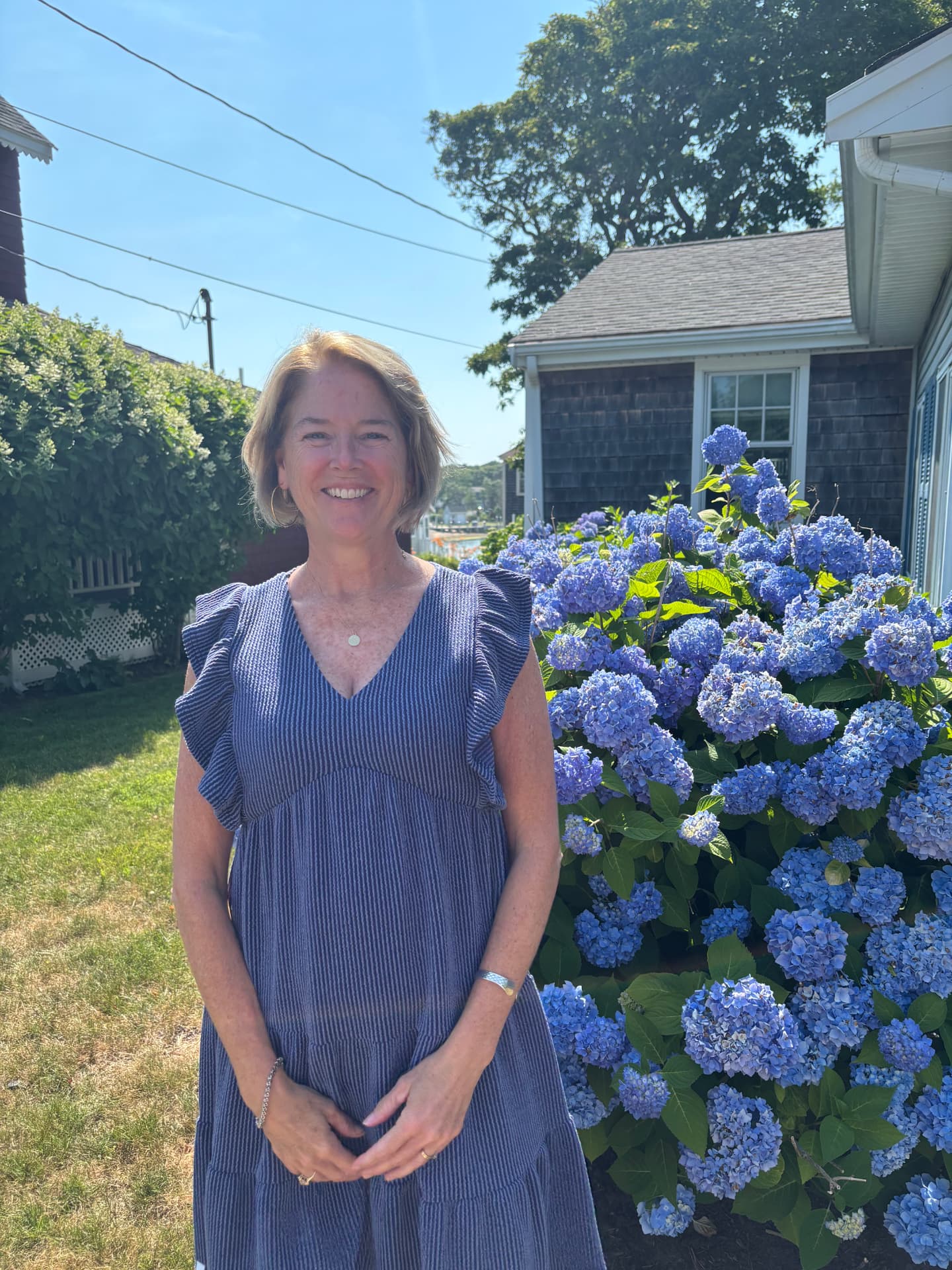 Sue standing outside by blue hydrangeas