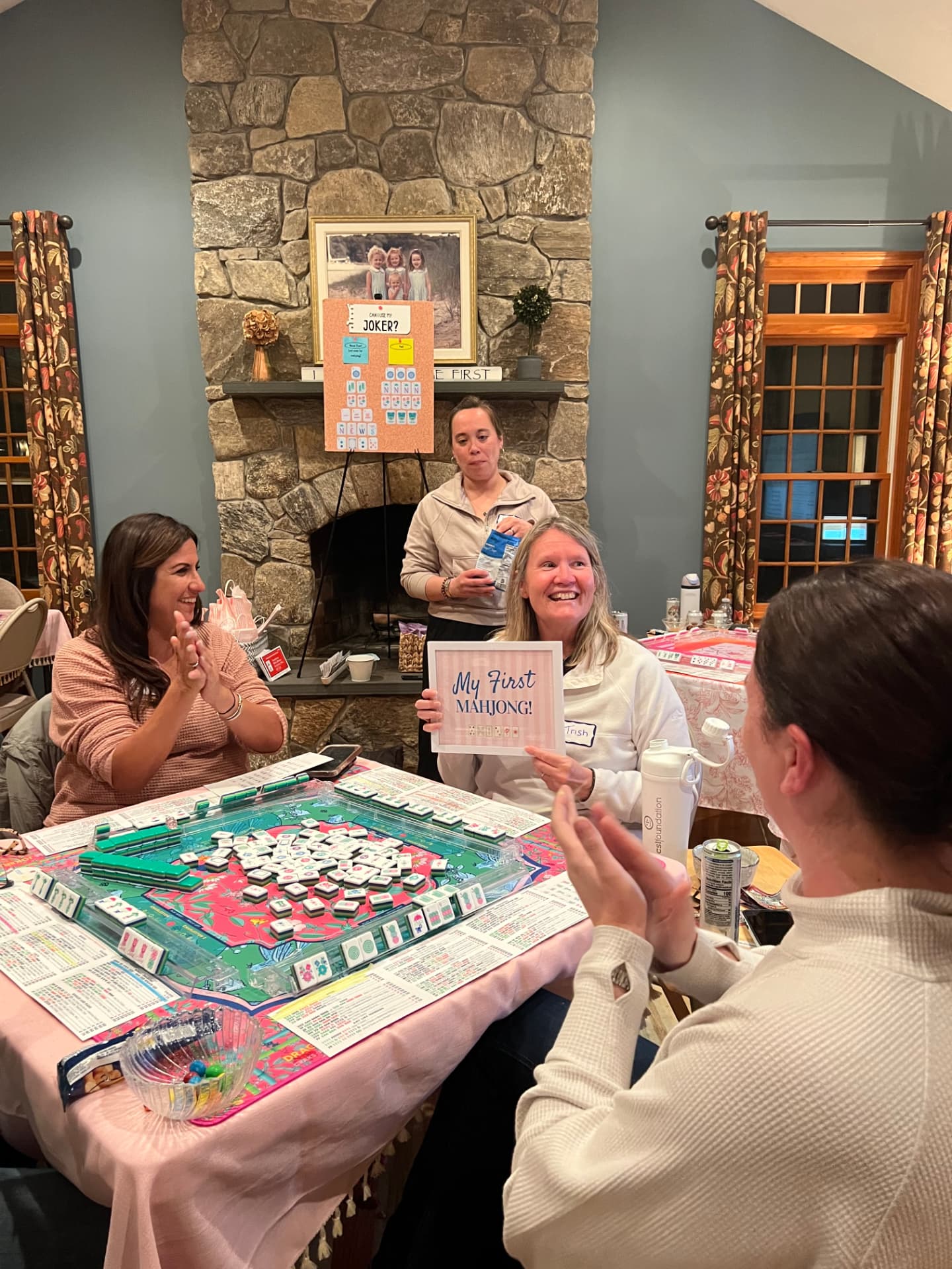 A student holding a My First Mahjong! sign while the table applauds